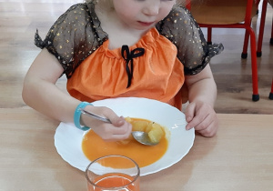 Gabrysia zjada zupę marchewkową.